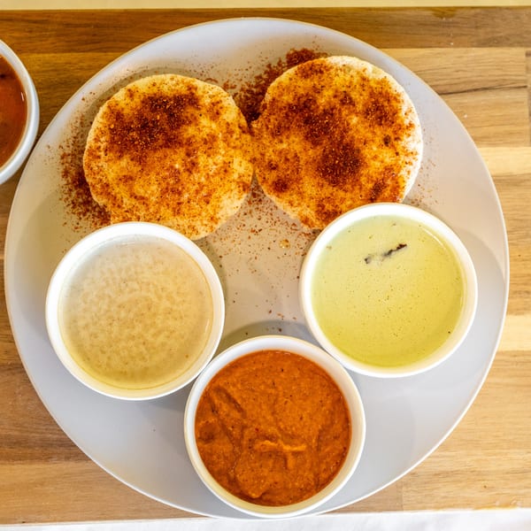 Two idlis topped with spice powder, served with three small bowls of colorful chutneys.